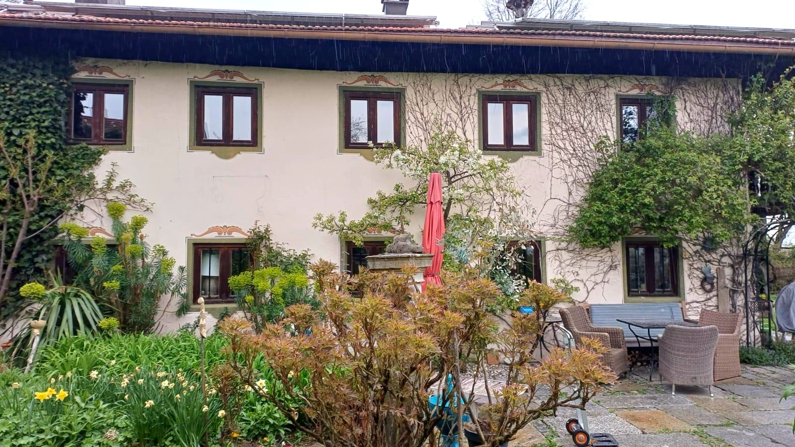 Südfassade des Scharamer Hofs mit bemalten Fensterlaibungen, Terrasse und Sitzgruppe