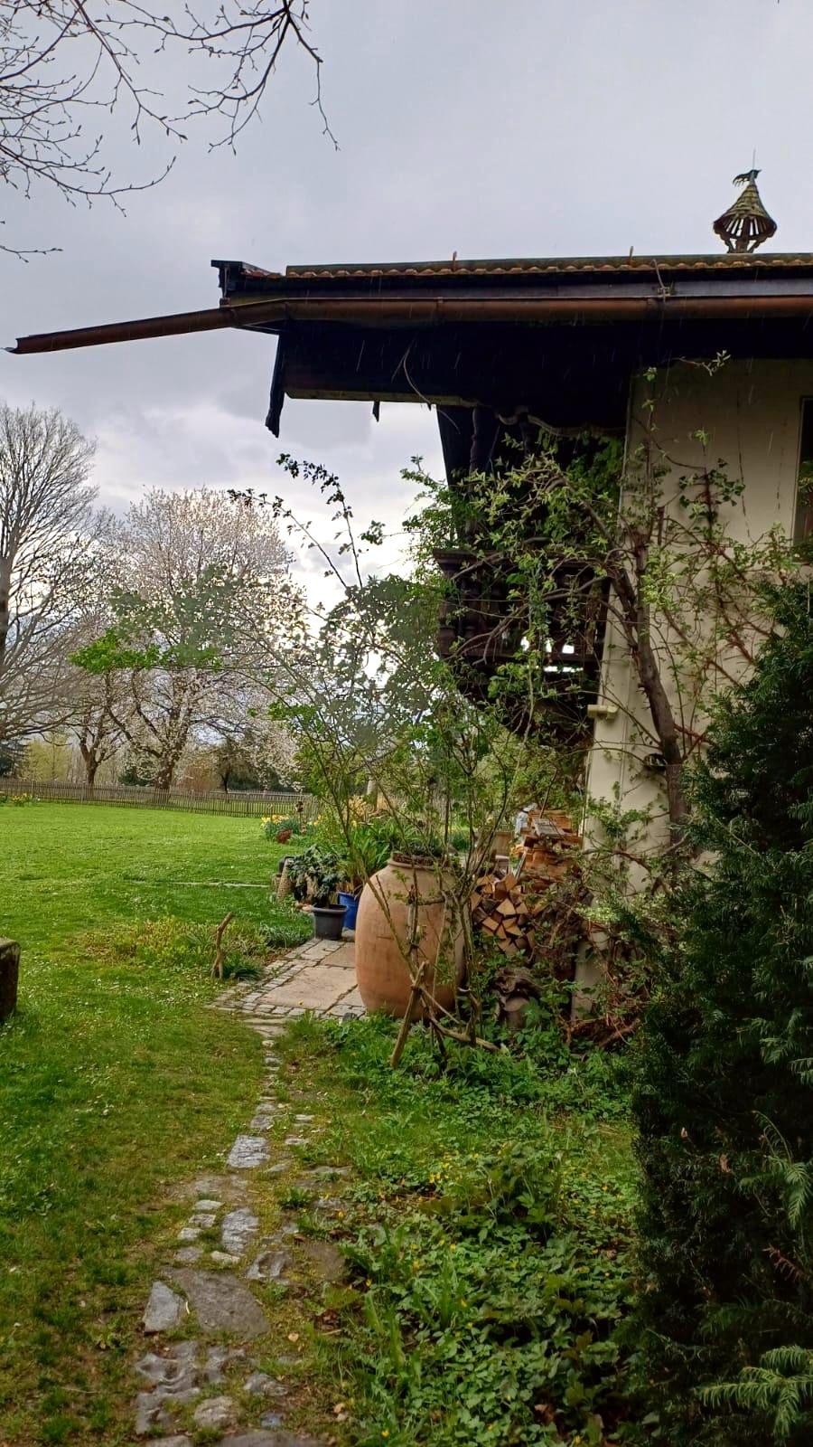 Hausecke mit weit vorstehendem Dach, Terrakotta-Amphore und gestapeltem Brennholz